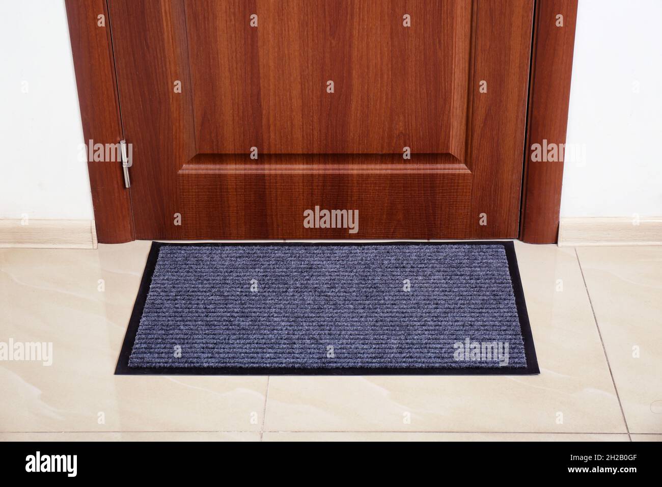 Modern welcome mat at door in hall Stock Photo