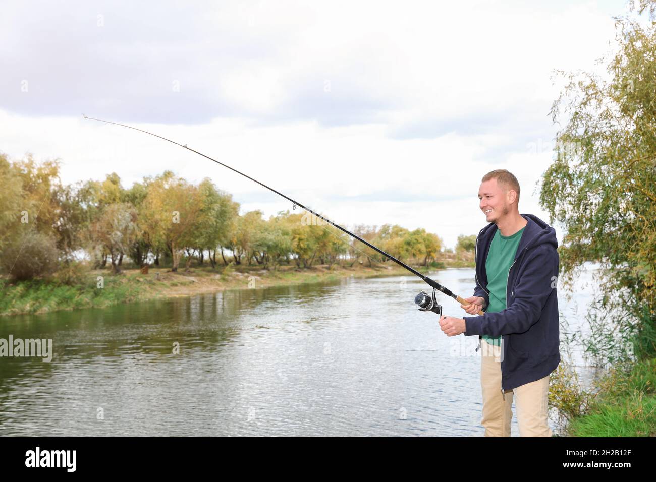 Man with rod fishing at riverside. Recreational activity Stock