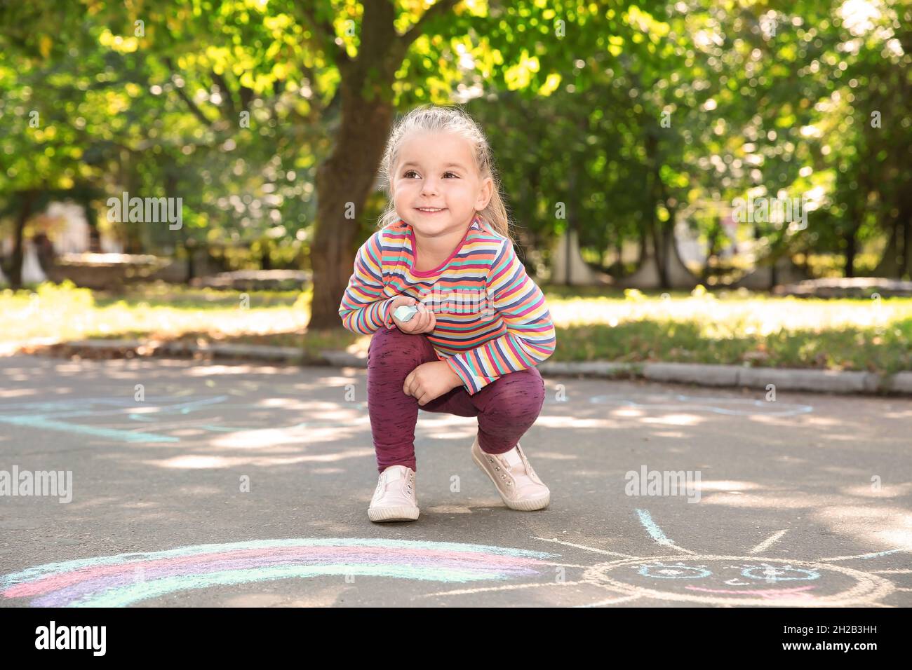 Little child drawing with colorful chalk on asphalt Stock Photo - Alamy