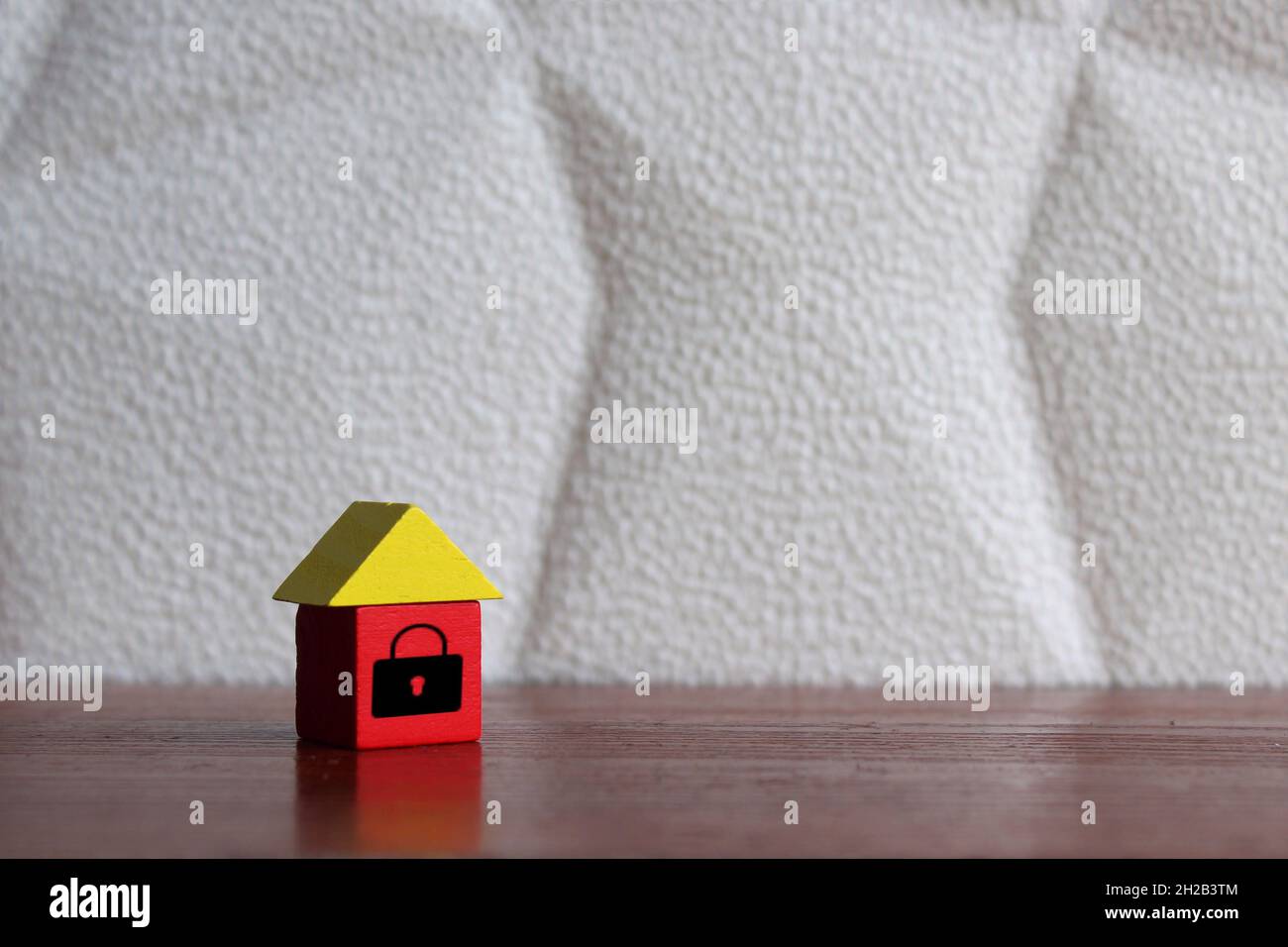 Security, safety and house insurance concept. Wooden house with padlock icon on table. Copy space for text. Stock Photo