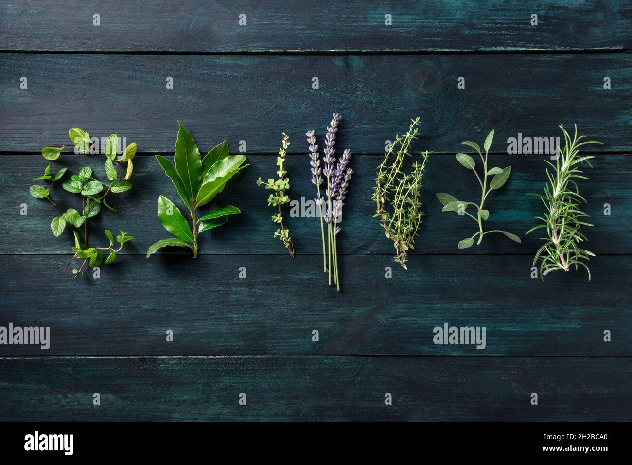 Fresh aromatic herbs, overhead flat lay shot on a dark wooden background. Rosemary, lavender
