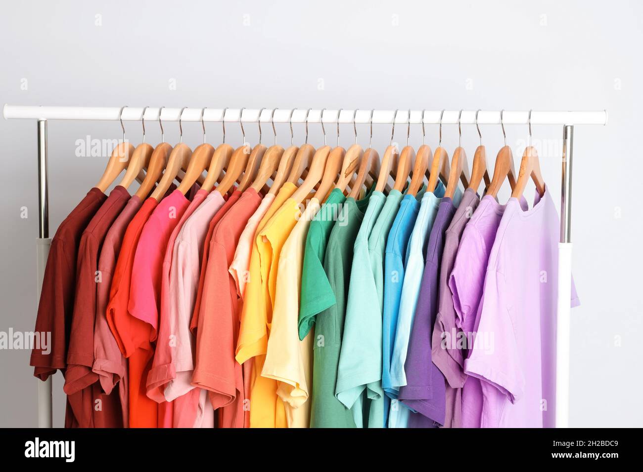 Rack with rainbow clothes on light background Stock Photo - Alamy