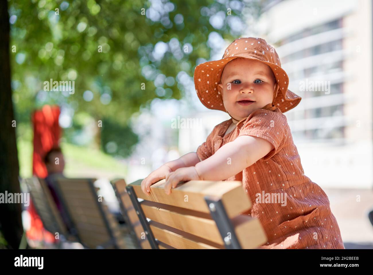 Portraits of a cute 10 months old baby girl. Walking on the playground, on a sunny summer day. Stock Photo