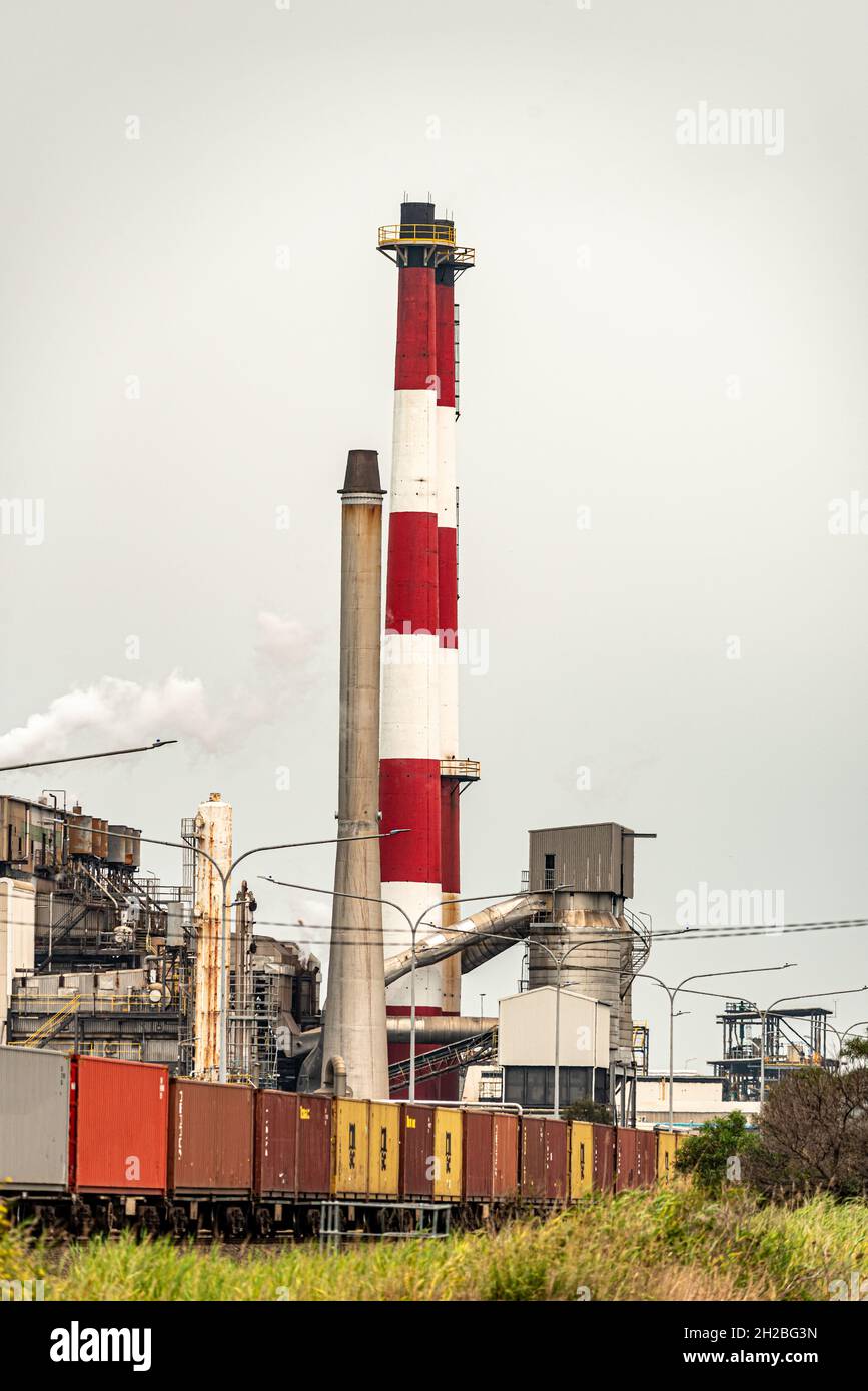 red and white smoke exhaust stacks with a train driving passed Stock Photo