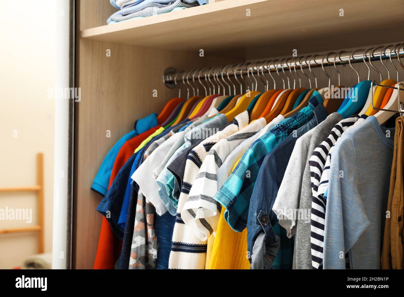 Hangers with teenage clothes on rack in wardrobe, closeup Stock Photo