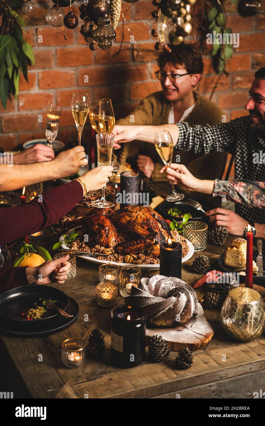 People clinking glasses over Christmas festive table with dinner Stock Photo