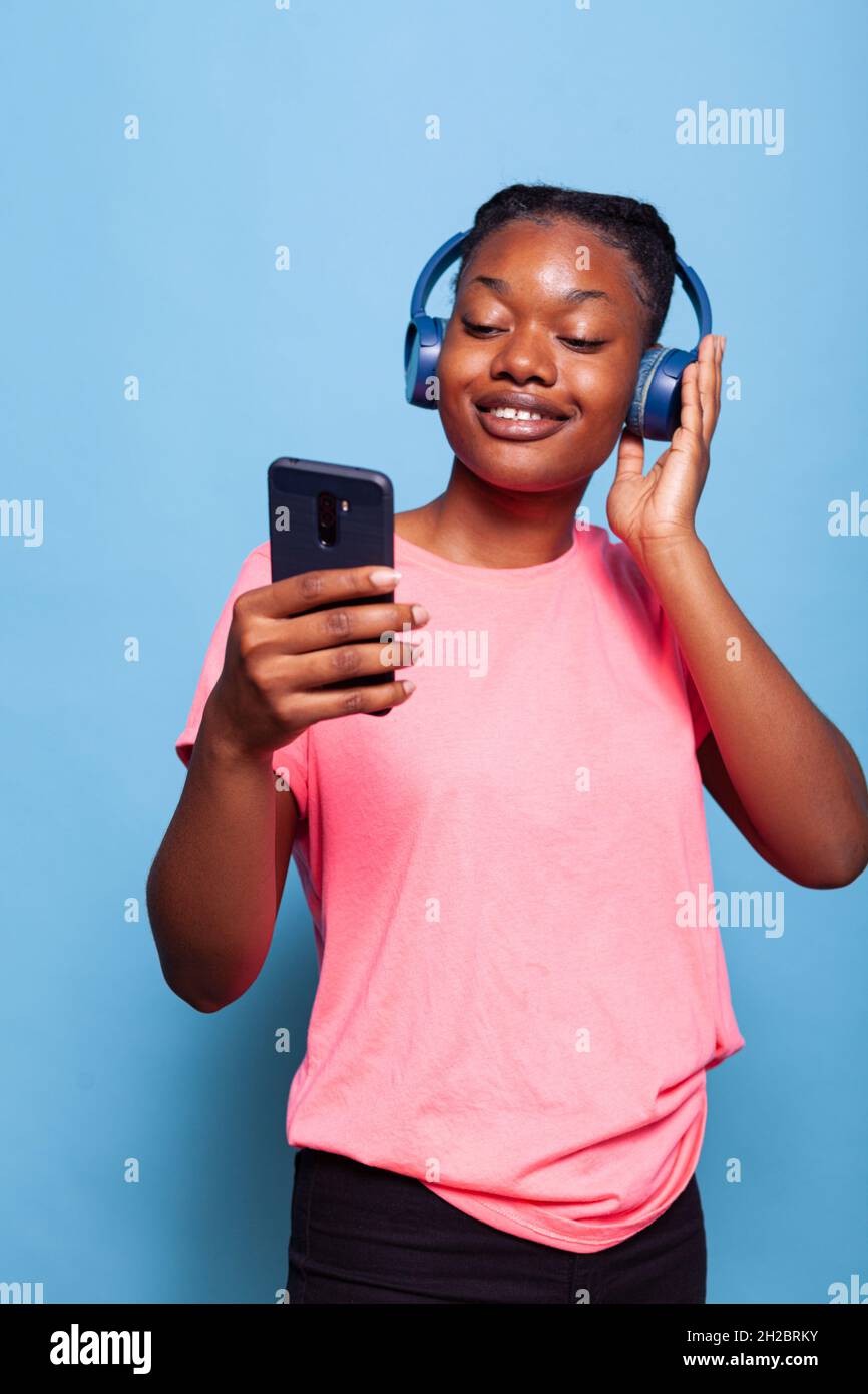 African american student with headphones holding smartphone searching ...
