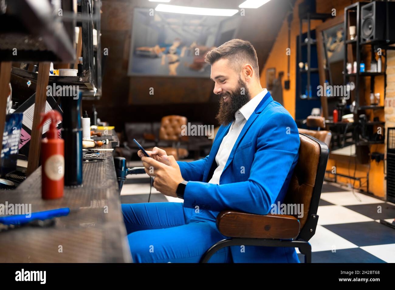 Male businessman in a suit using a smartphone in a hair salon Stock Photo