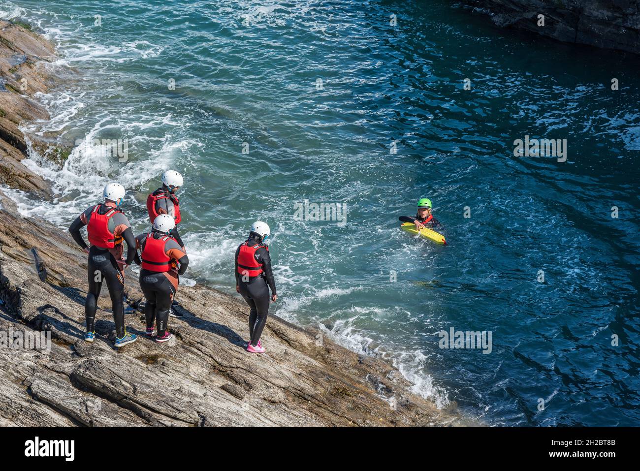 Holidaymakers and their coasteering guide on the coast of Towan Head in Newquay in Cornwall. Stock Photo