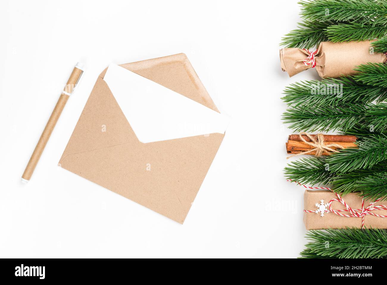 christmas card of craft envelope and craft pen with frame of fir branches, gift boxes on isolated white background with copy space  Stock Photo