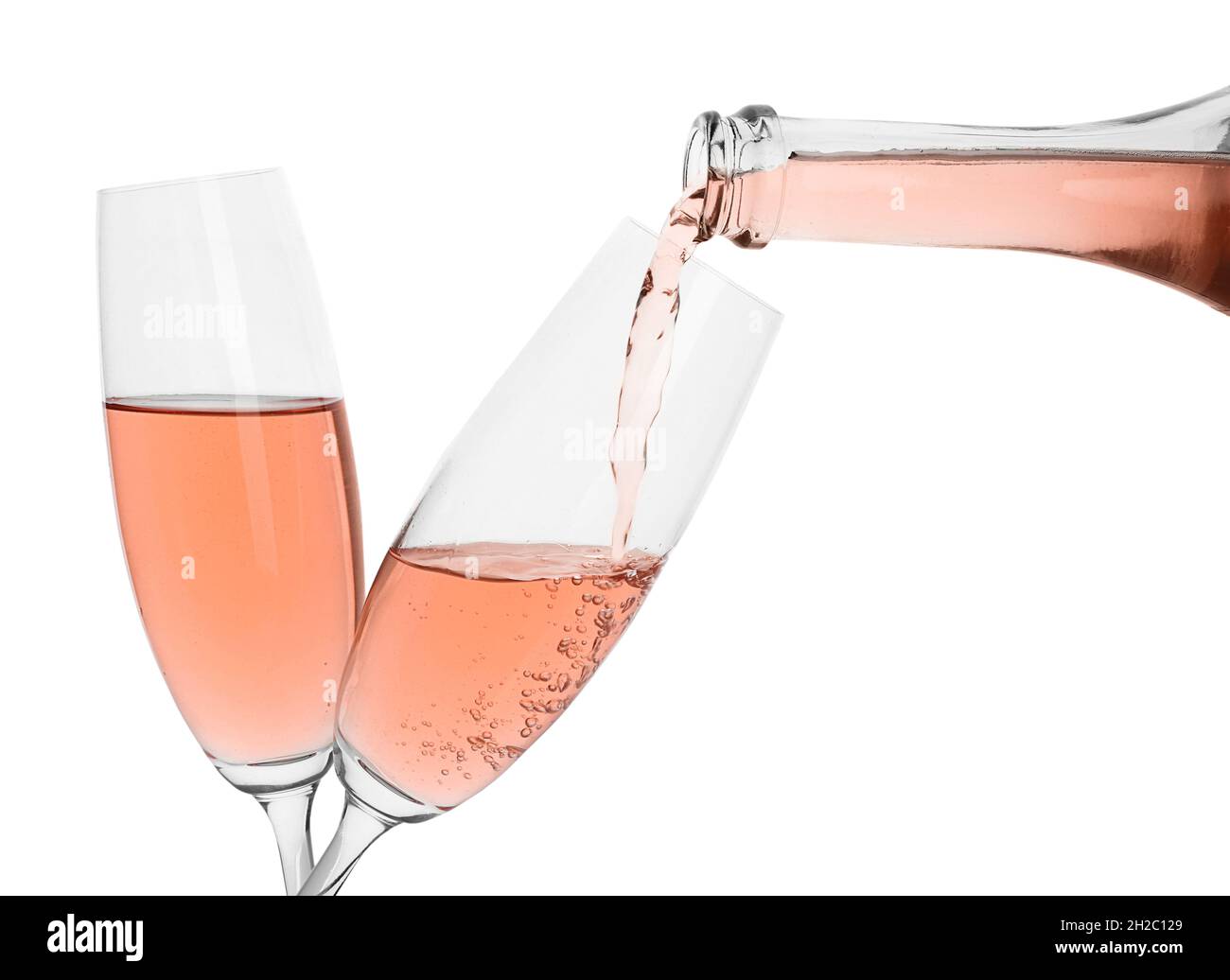 Pouring rose champagne from bottle into glass on white background Stock