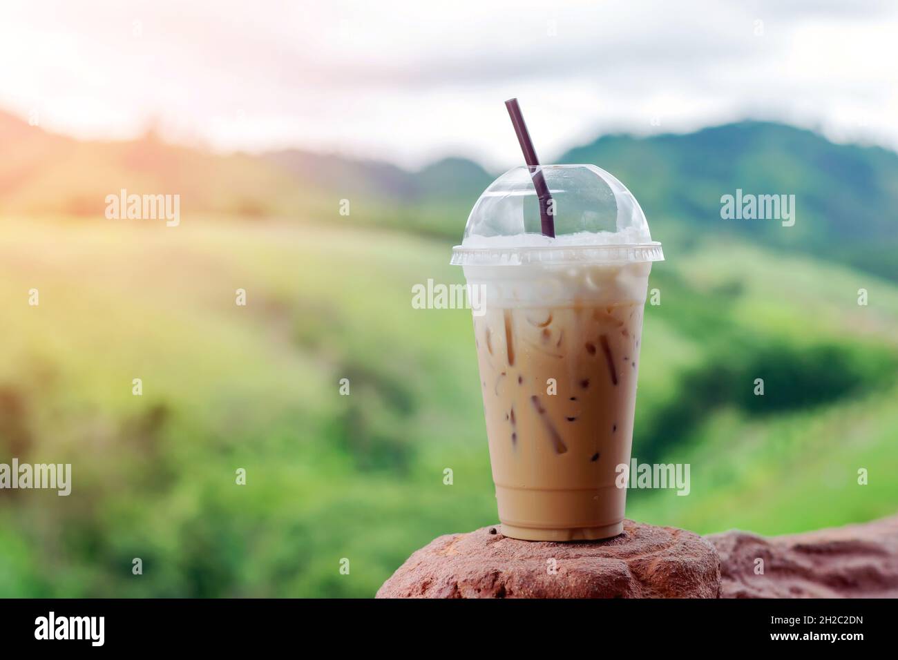 Closeup ice coffee in plastic cup with beautiful mountain background. Stock Photo