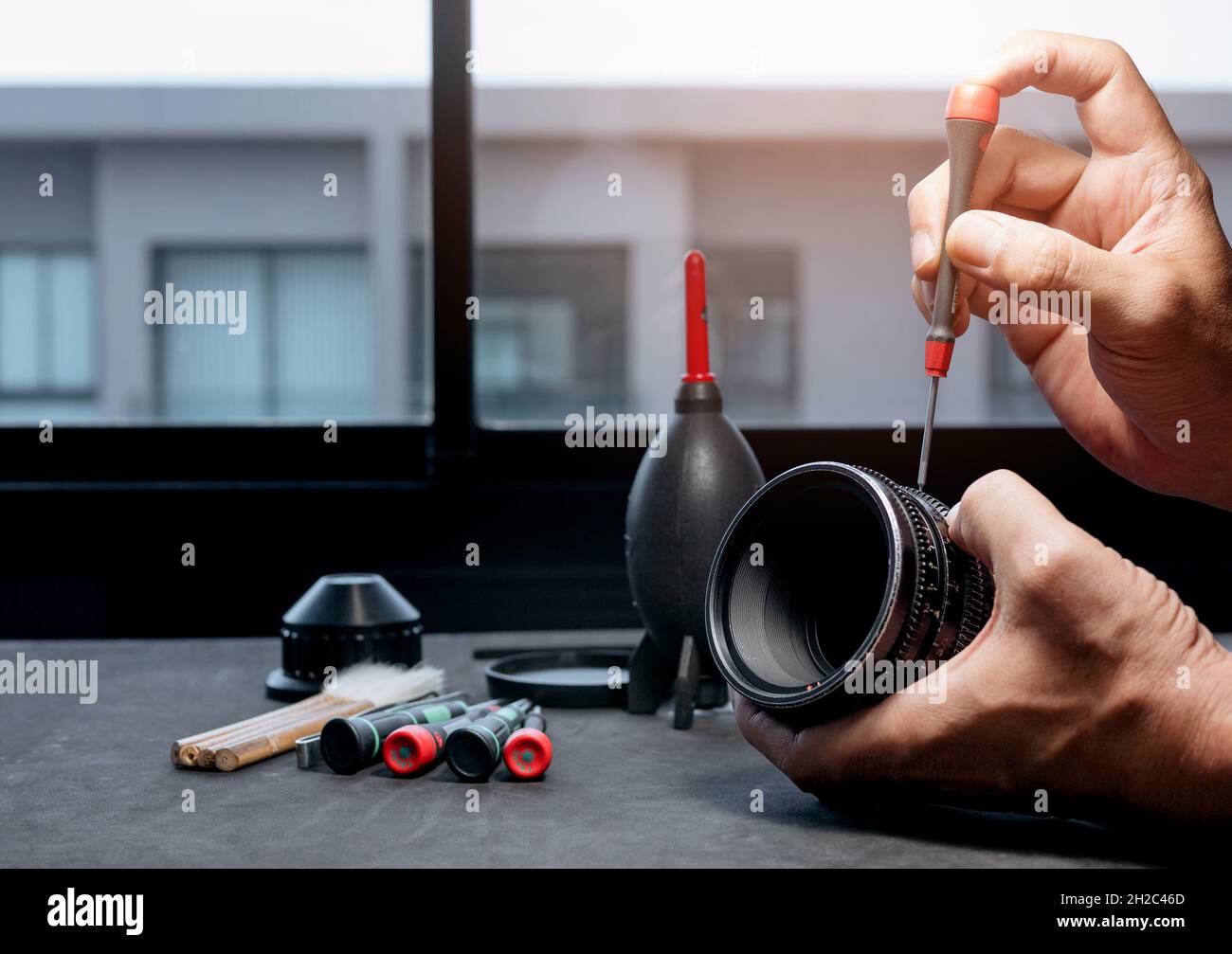 Man's hand using a screwdriver to remove screws on the barrel of a