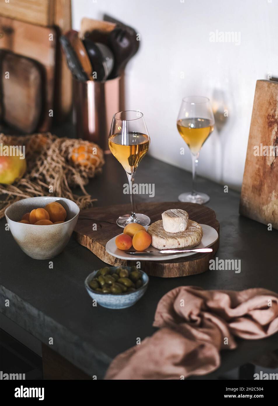 Orange wine in glasses, fruits and cheese on wooden board Stock Photo