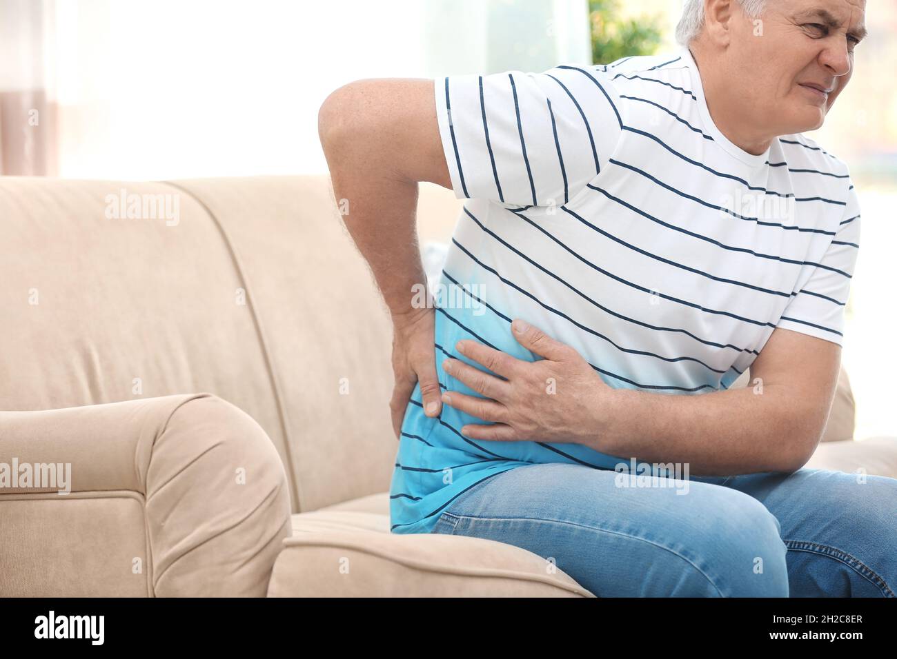 Mature man suffering from back pain at home Stock Photo - Alamy