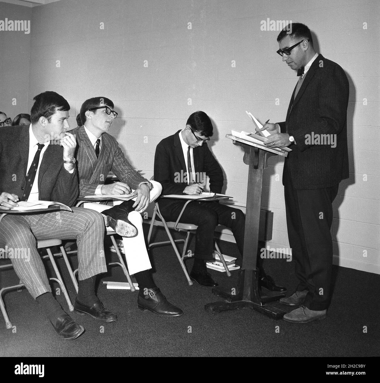 1960s, historical, well-dressed male students in a philosophy class sitting up close to a male lecturer standing at a wooden lectern, USA Stock Photo
