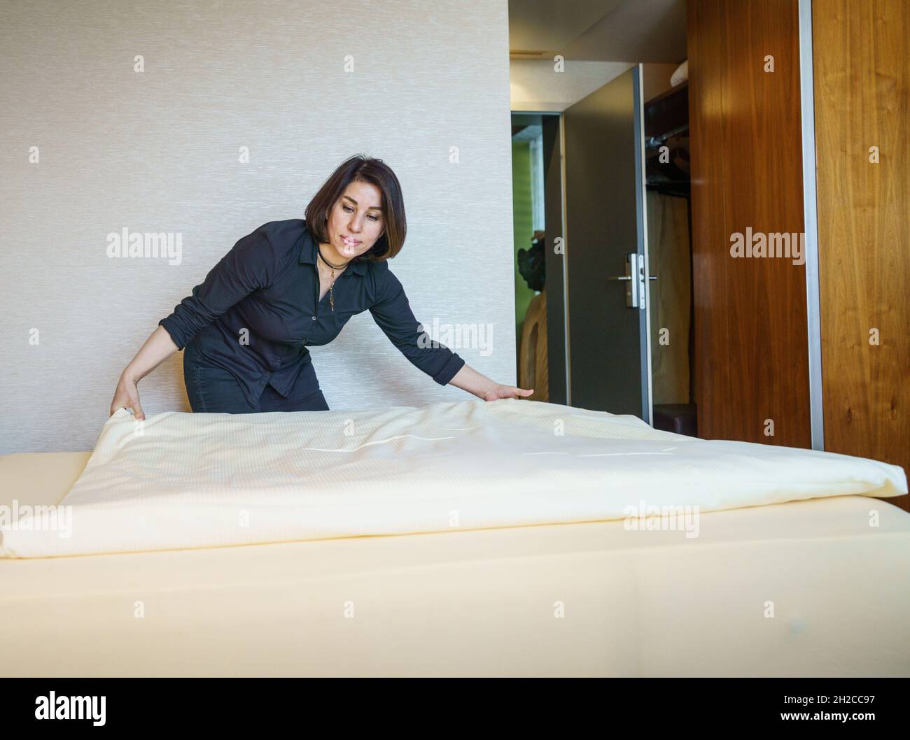 21 October 2021, Rhineland-Palatinate, Mainz: Housekeeper Forough Mokhtari makes a bed in one of the rooms at the Hotel Atrium in Mainz. At the same time, a press conference of the Rhineland-Palatinate Chambers of Industry and Commerce took place in the hotel on the new employer network 'Working Family', to which about 25 family businesses from the hotel and restaurant industry belong. Numerous employees in the hospitality industry have changed industries during the lockdowns in the pandemic, and the number of trainees has declined. This is where the network comes in. Photo: Frank Rumpenhorst/ Stock Photo