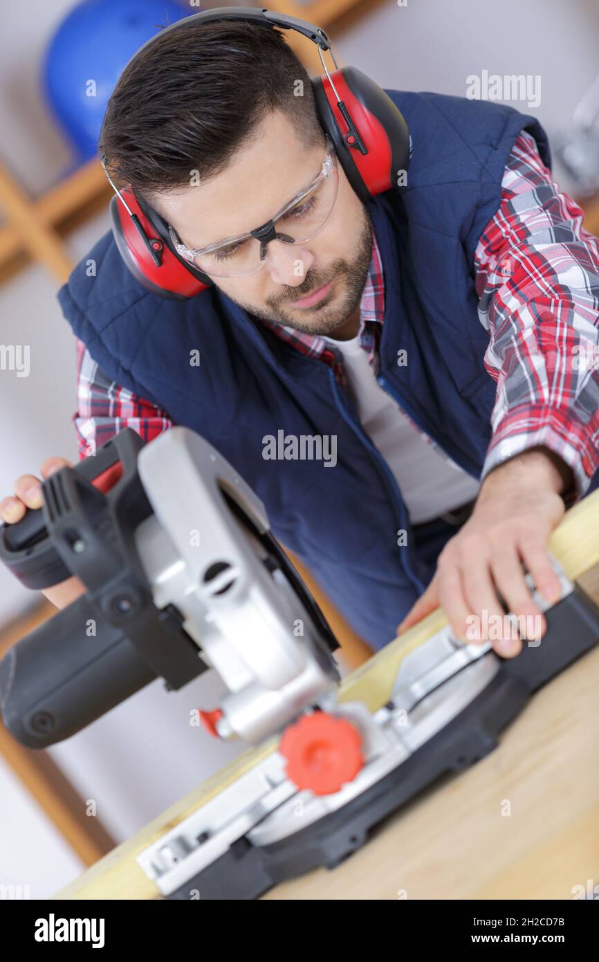 carpenter cutting flaxboard using sliding compound mitre saw Stock Photo
