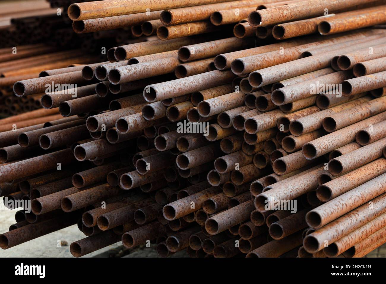 Many small-diameter metal pipes for gasification and construction lie in a stack in an open warehouse on the street. Solid industrial background for the supplier of metal pipes. New products. Stock Photo