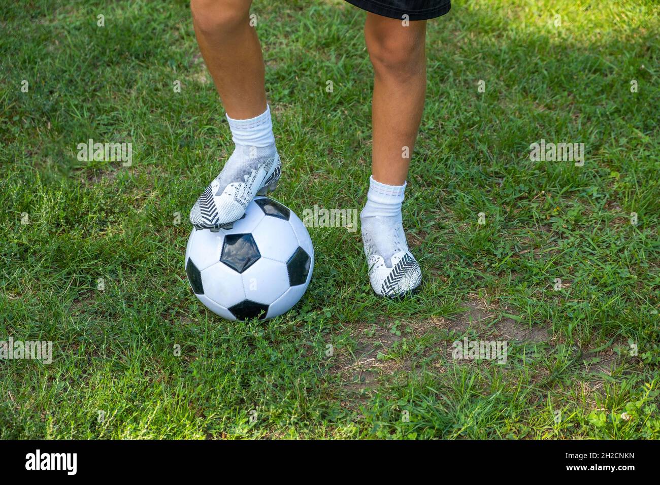 Boy teen puts his leg on ball on soccer field. Training, active