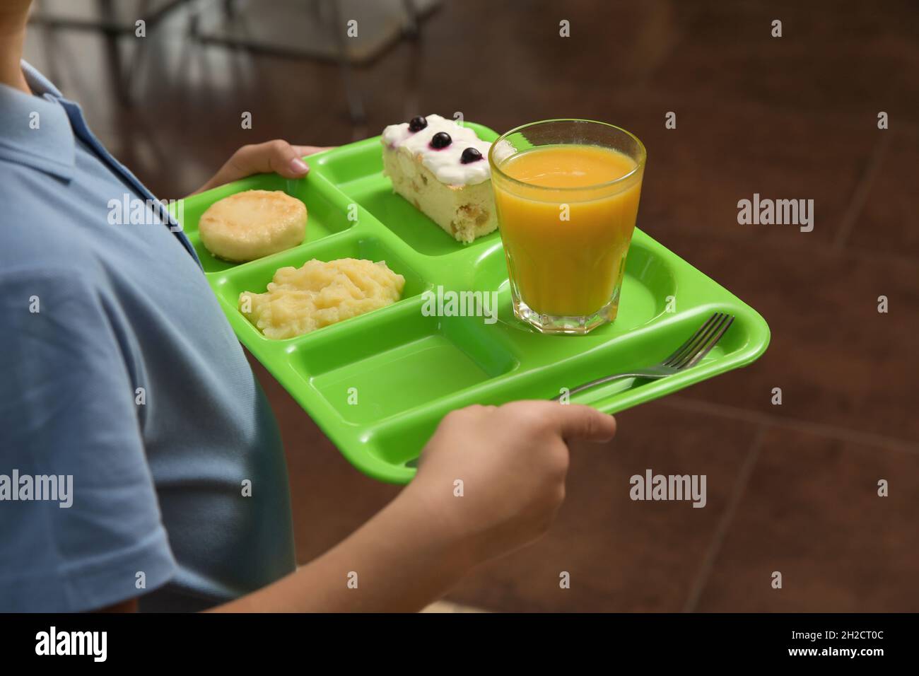 Boy holding tray with healthy food in school canteen, closeup Stock