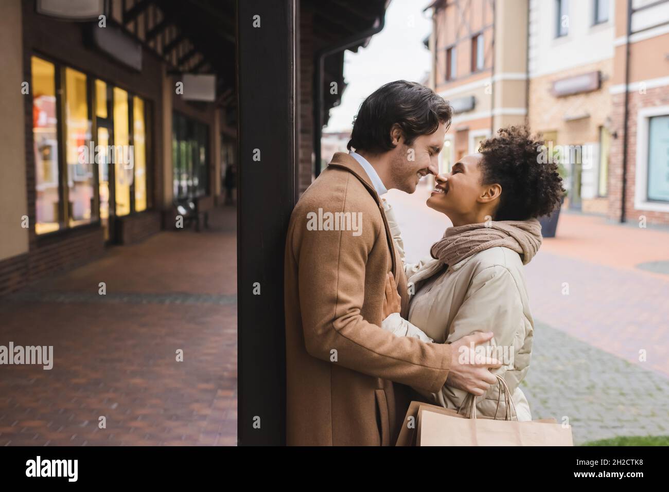side view of cheerful african american woman hugging boyfriend with ...