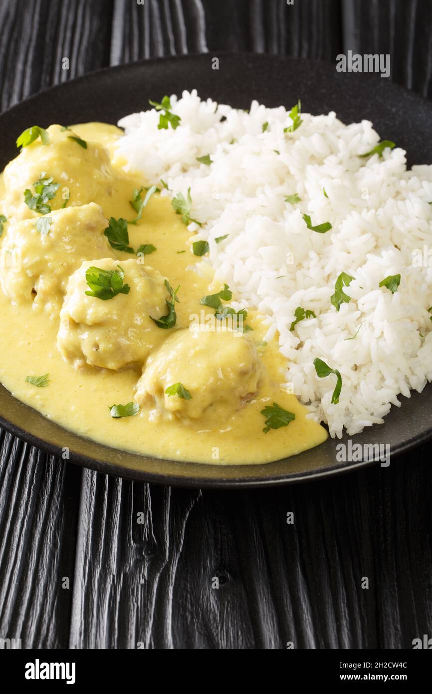 Boller i Karry Pork Meatballs in mild Curry with rice close up in the plate on the table. Vertical Stock Photo
