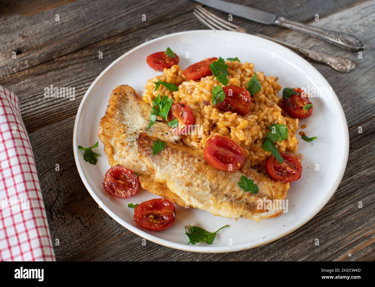 Sauteed fish with rice and vegetable on a plate on rustic and wooden table Stock Photo
