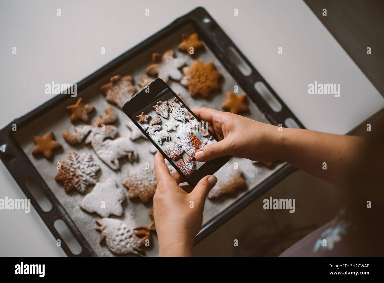 Woman takes photo on smartphone Christmas gingerbread sprinkled Stock Photo