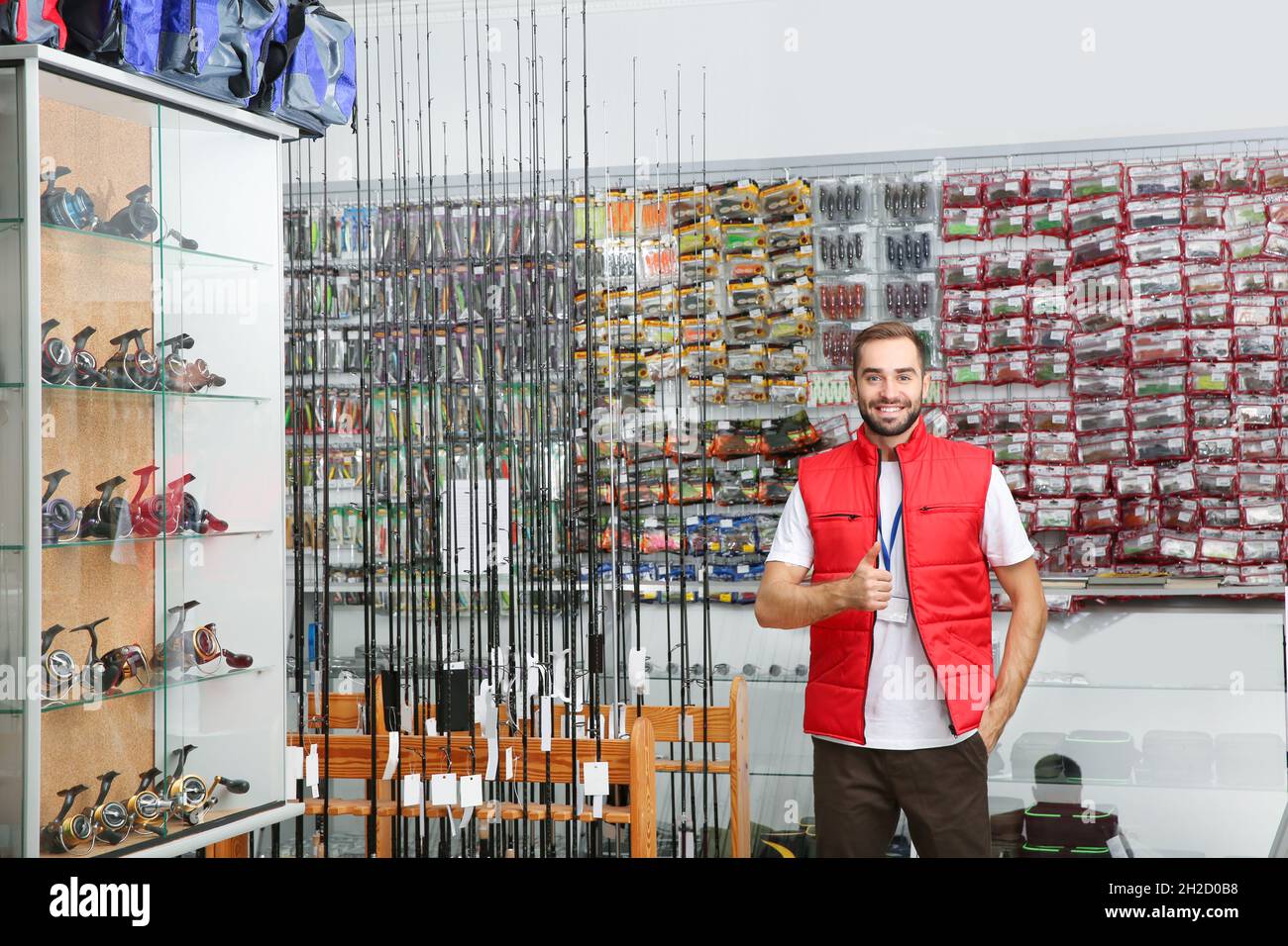 https://c8.alamy.com/comp/2H2D0B8/salesman-standing-near-showcase-with-fishing-equipment-in-sports-shop-space-for-text-2H2D0B8.jpg