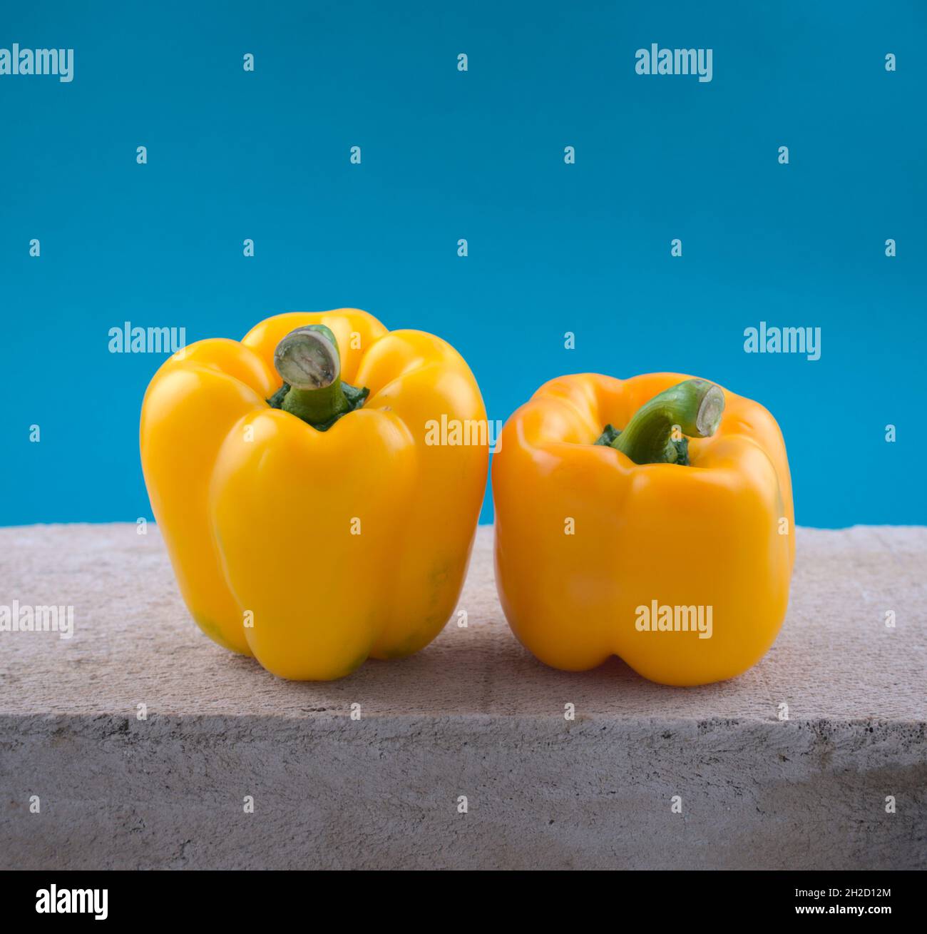 Fresh organic yellow bell peppers veggie on grunge cement texture slate against blue abstract background. Food, still life, wall art image style. Stock Photo