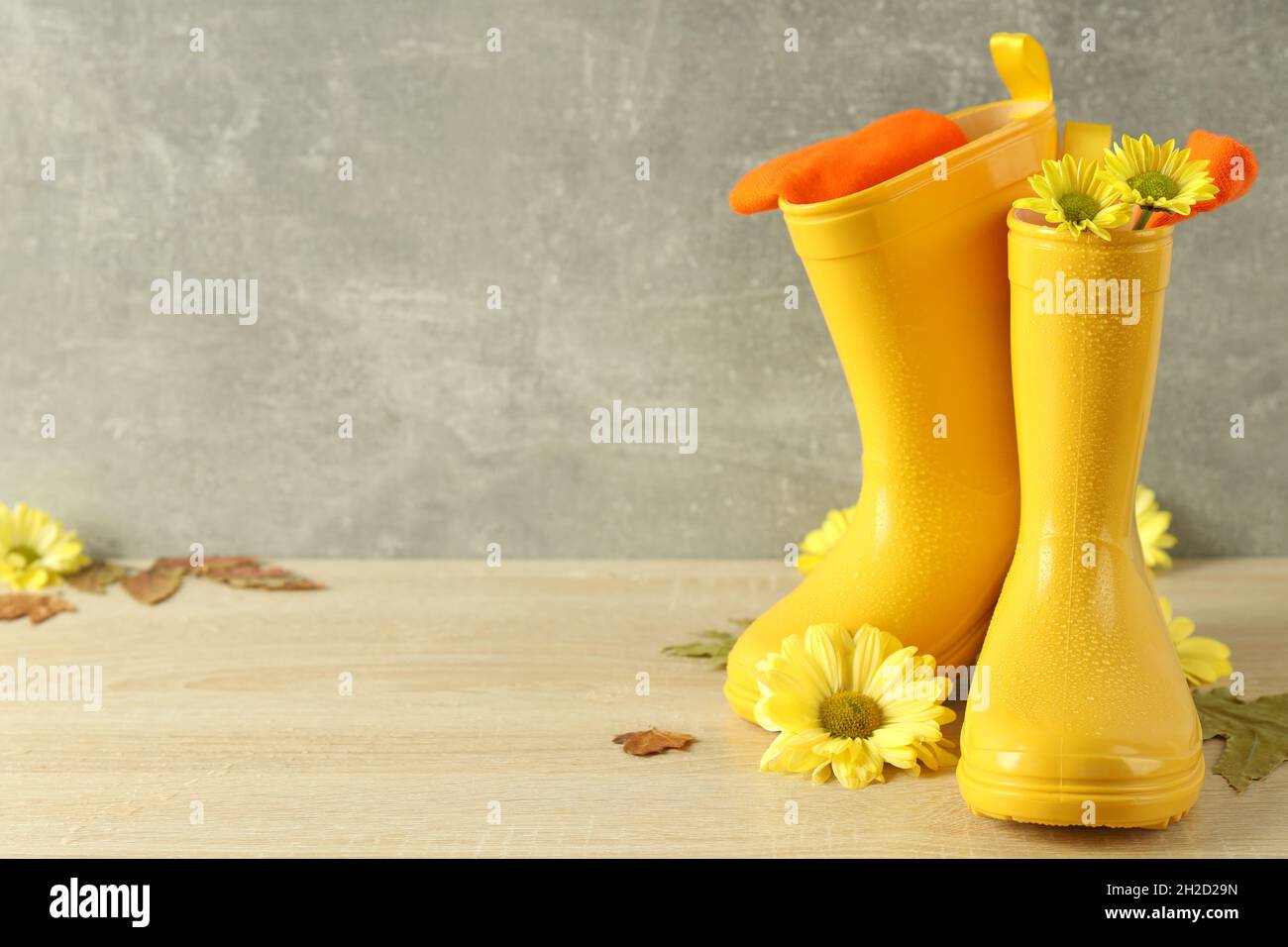 Rubber boots with flowers on wooden table with leaves Stock Photo - Alamy