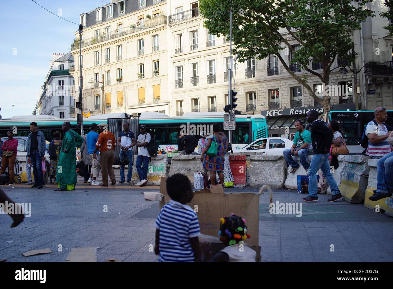 African migrant children play, hiding behind a broken cardboard box, on the pavement of the mixed African/North African... neighbourhood - Chateau Rouge, Goutte d'Or, 75018 Paris, France Stock Photo