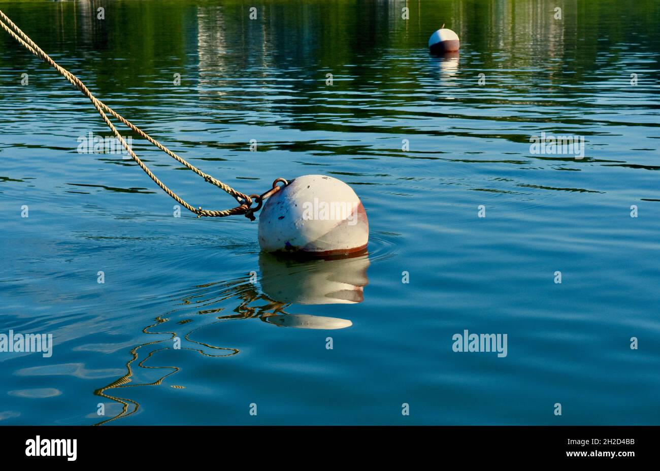 Mooring ball anchoring lines from a unseen boat. Water is a vivid blue with interesting surface patterns. Copy space. Background. Stock Photo