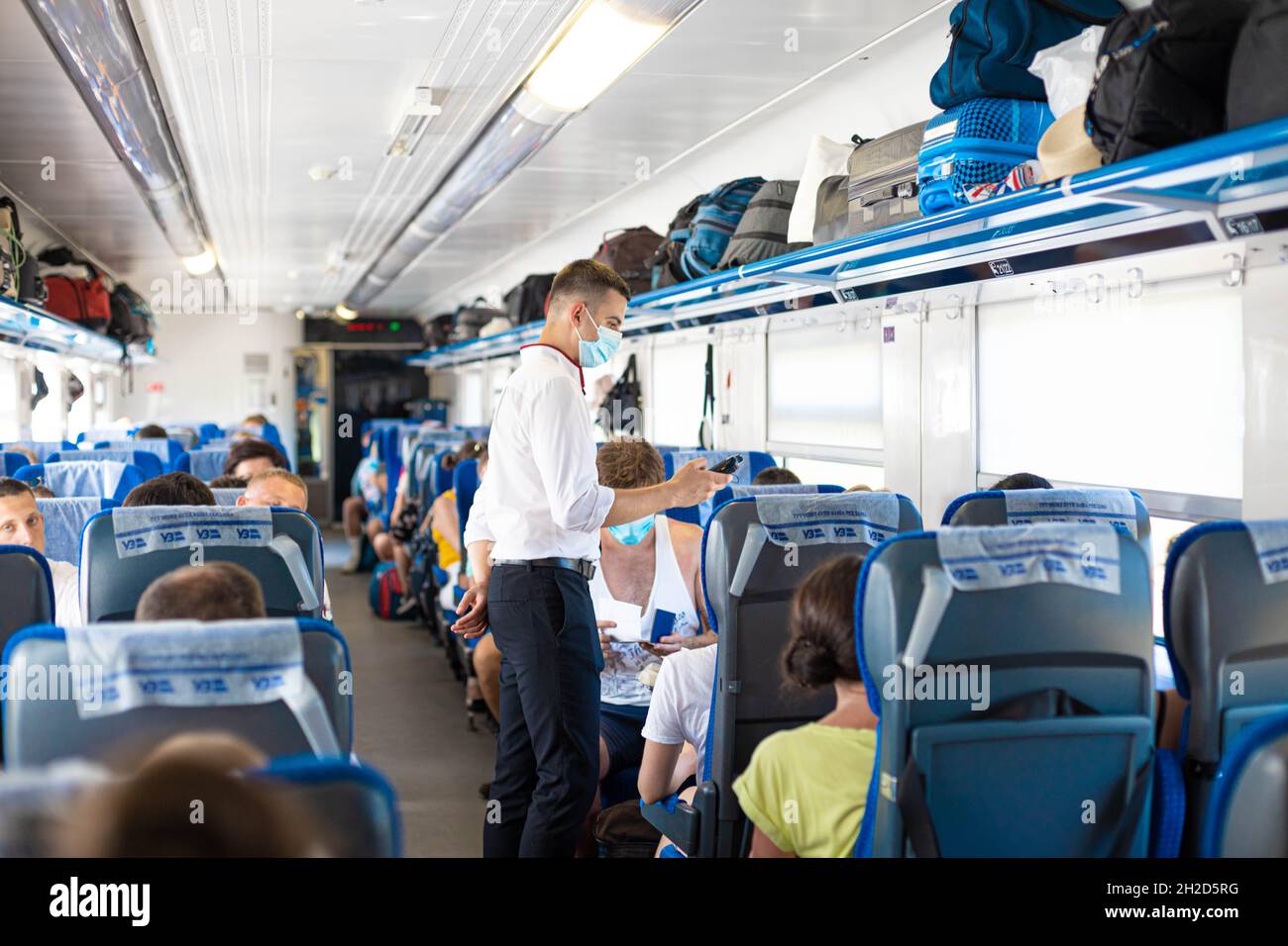 Odessa, Ukraine August 2020: Train conductor checks the tickets of the travelers on the international train. People traveling by train Stock Photo