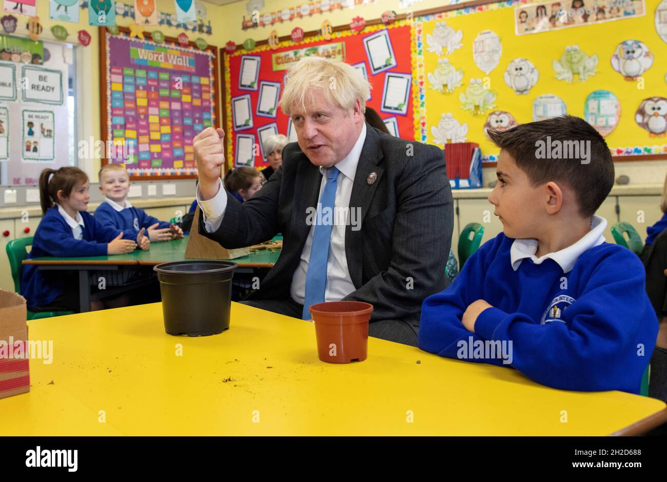Prime Minister Boris Johnson joins schoolchildren as they plant seeds for trees during a visit to Crumlin Intergrated primary school in County Antrim. Picture date: Thursday October 21, 2021. Stock Photo