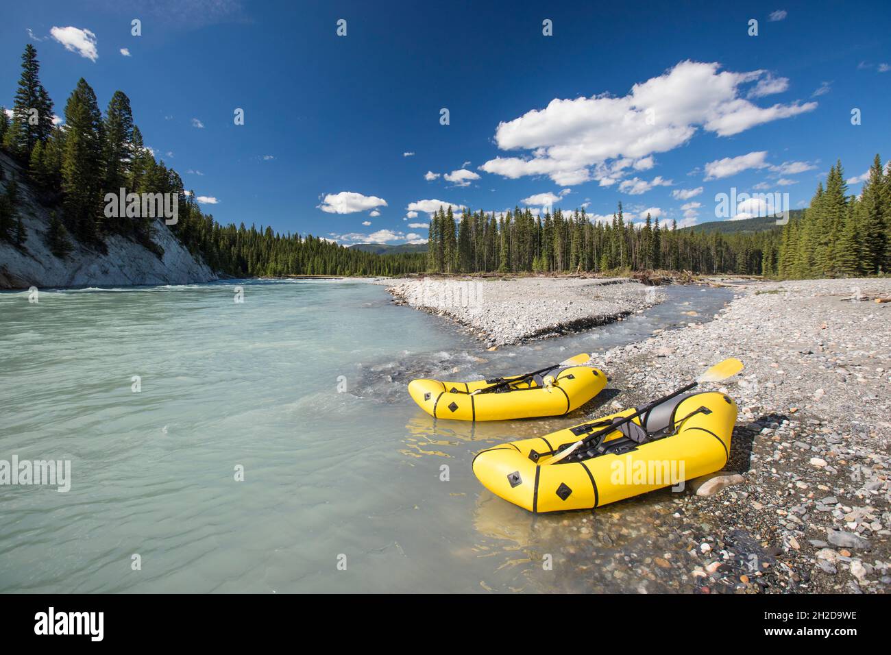 Two inflatable rafts on rocky shore next to river. Stock Photo