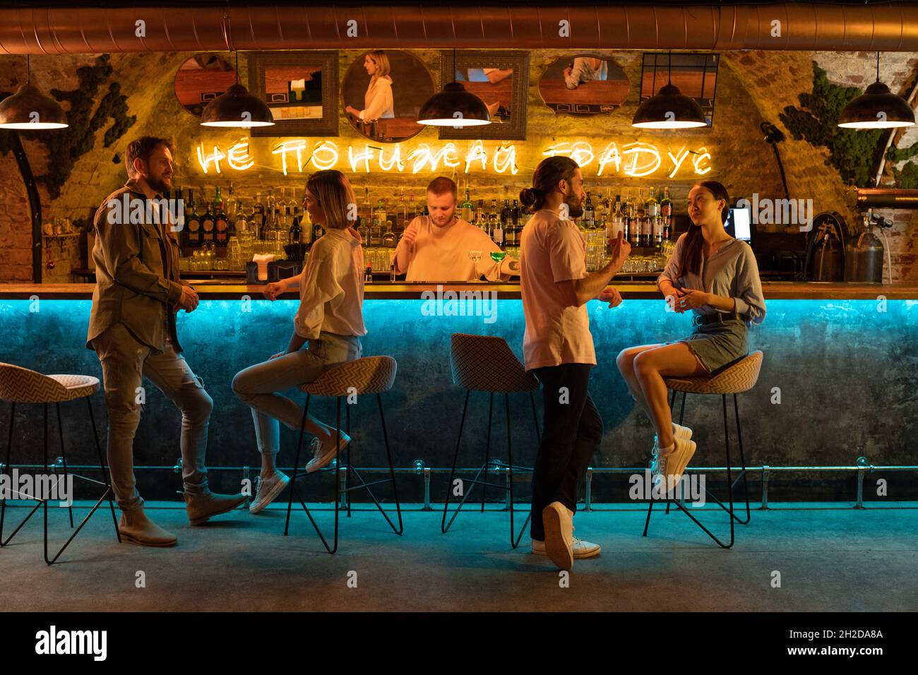 Diverse couples talking near counter and bartender during night party