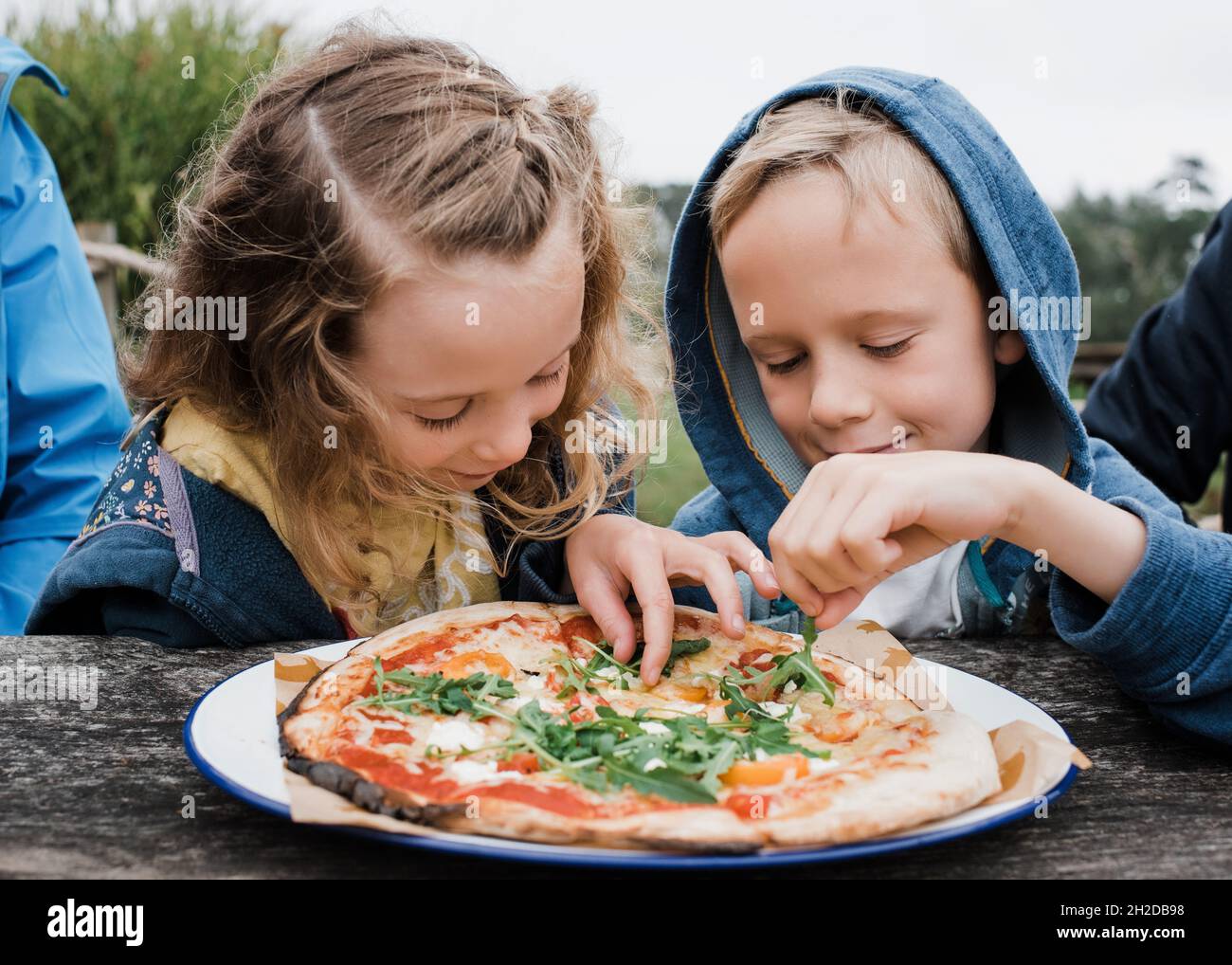 girl and boy sharing a pizza together at an outdoor restaurant Stock Photo