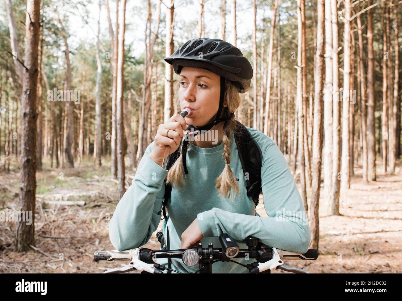 woman drinking from a bladder whilst out cycling in the forest Stock Photo
