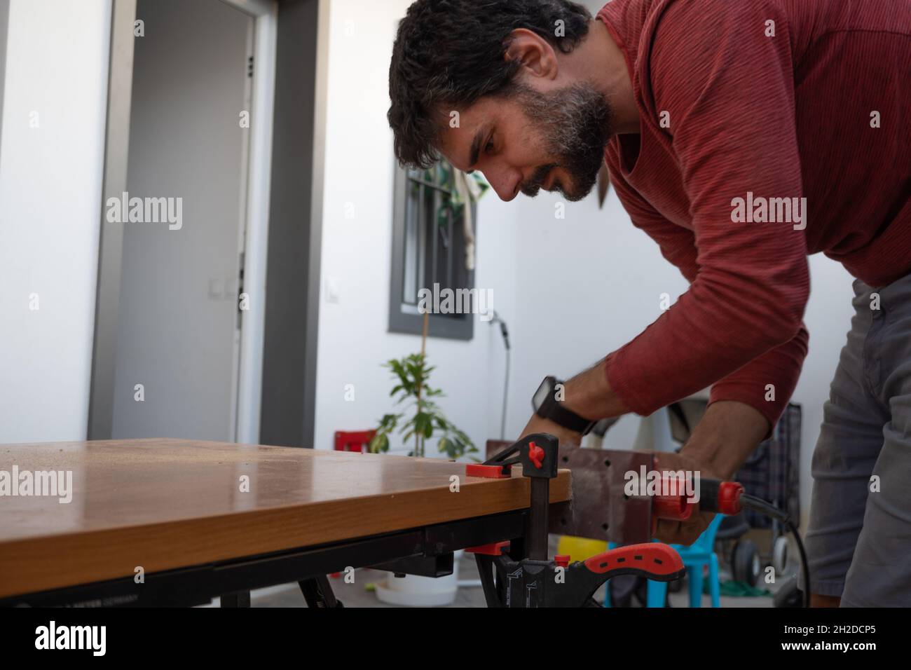 young man using carpenter's power tools making wooden furniture in his home Stock Photo