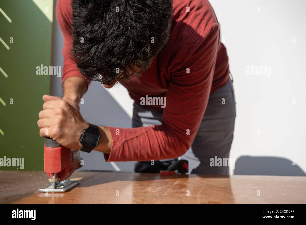 young man using carpenter's power tools making wooden furniture in his home Stock Photo