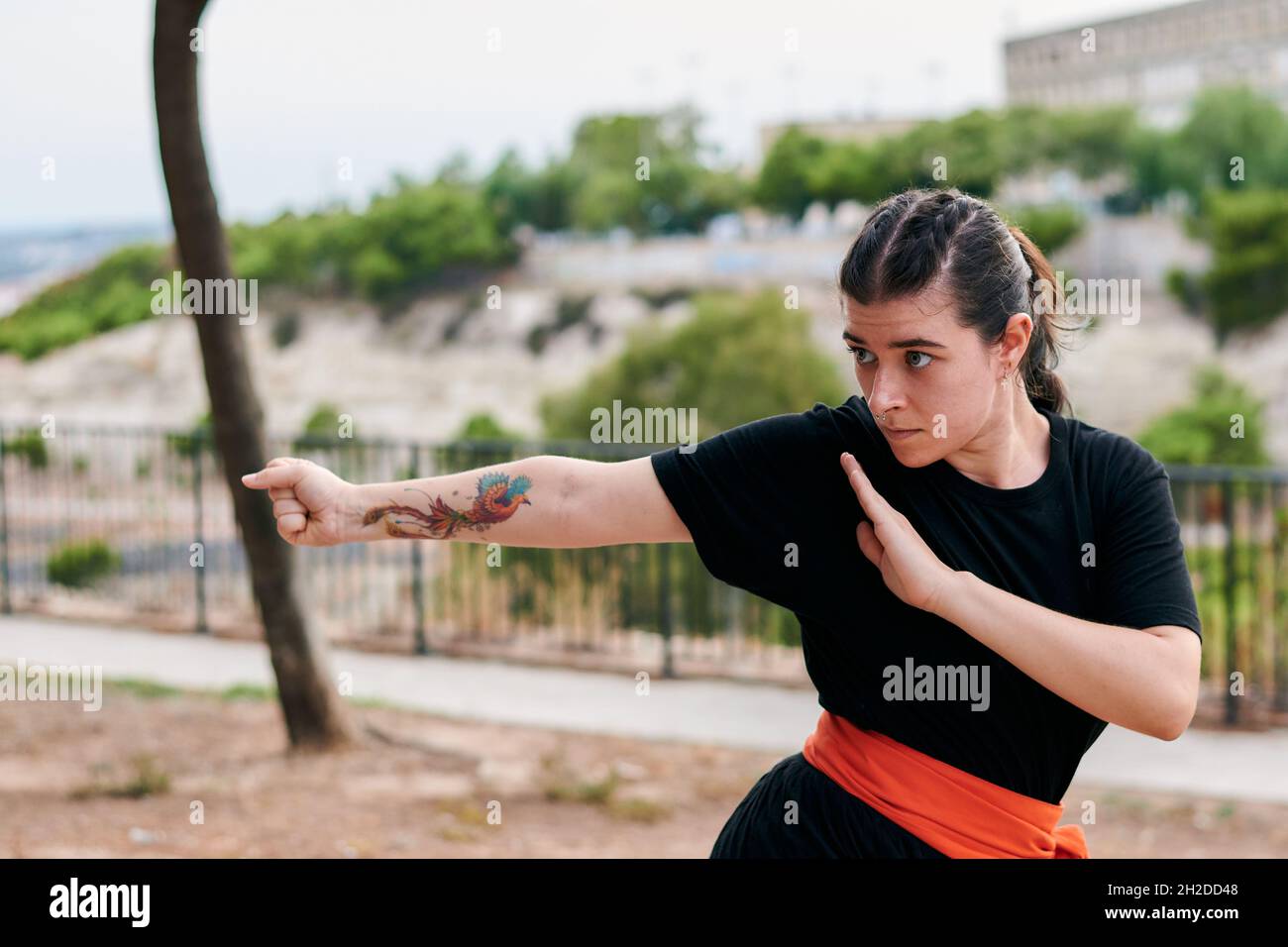 Woman with a tattoo training martial arts in a park Stock Photo