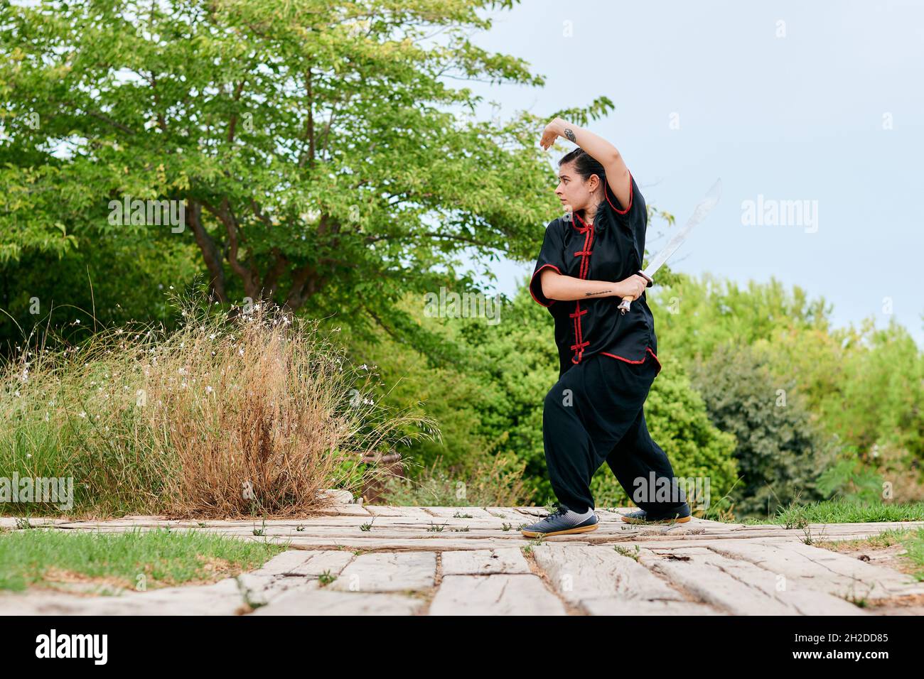 Woman training kung fu with a sword in a park Stock Photo