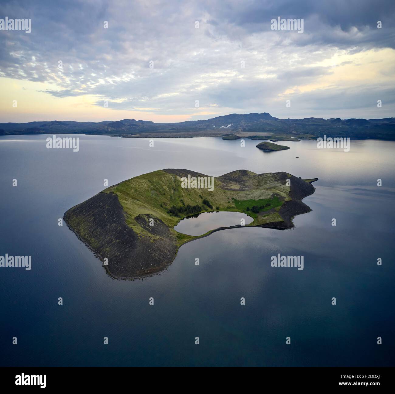 Amazing drone view of green island located in water of calm pond under sunset sky in Iceland Stock Photo