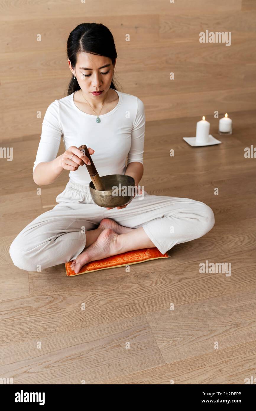 Asian girl using a Tibetan Singing Bowls, rin gongs, Himalayan bowls or suzu gongs Stock Photo