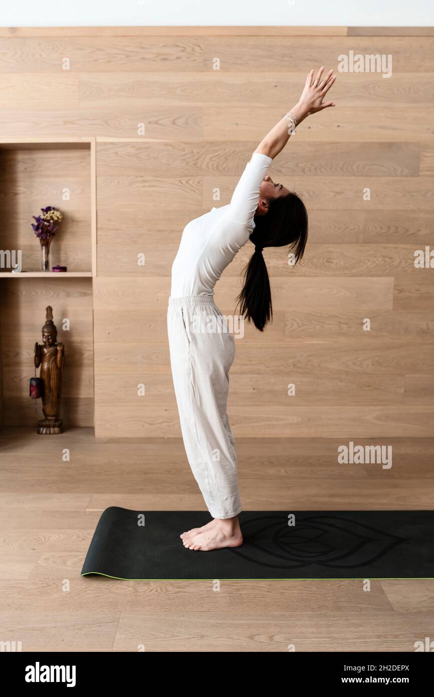 A woman practicing yoga performs back bend, Hasta Uttanasana pose Stock Photo