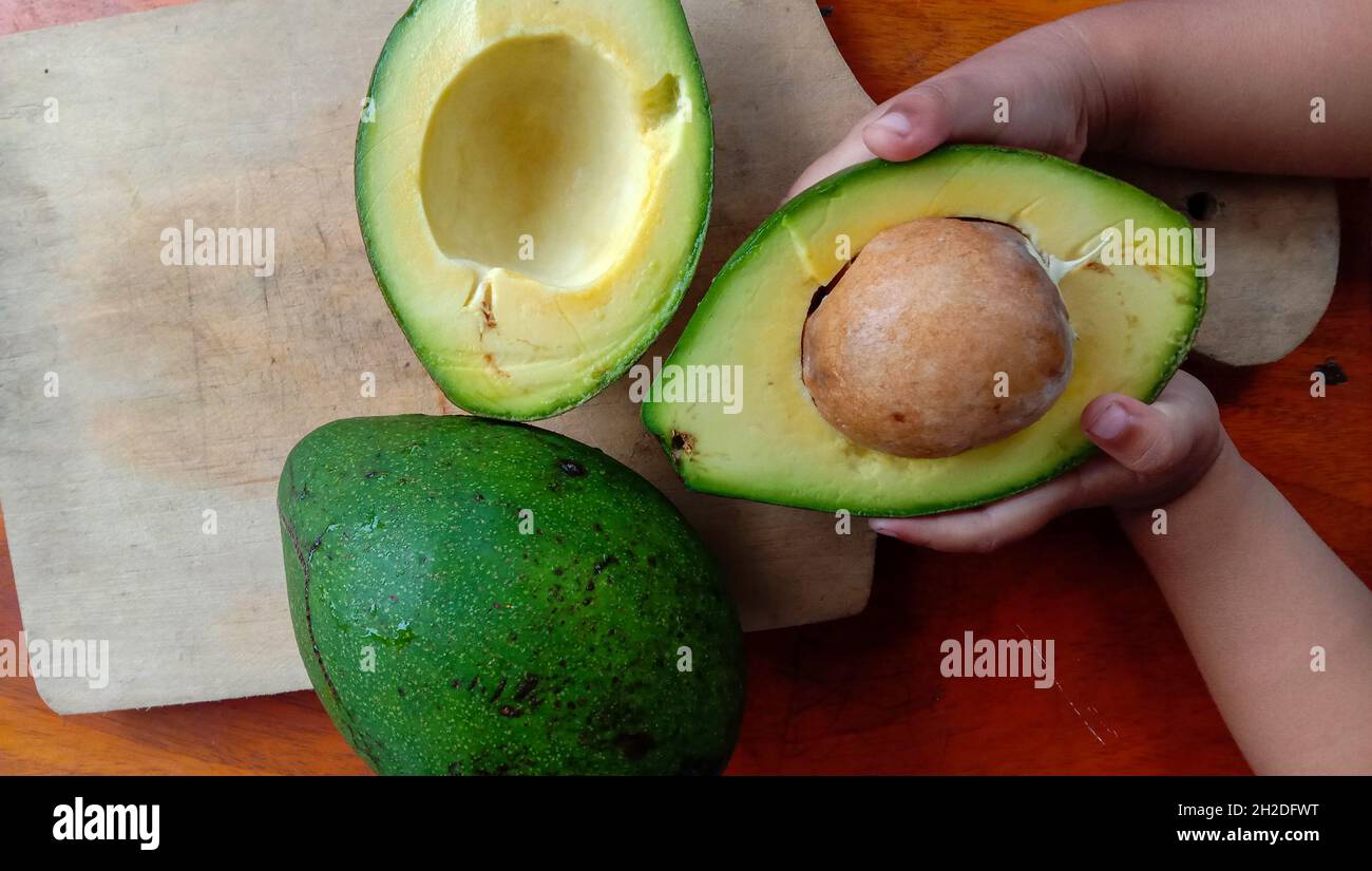 Hand holding split up avocados Stock Photo - Alamy