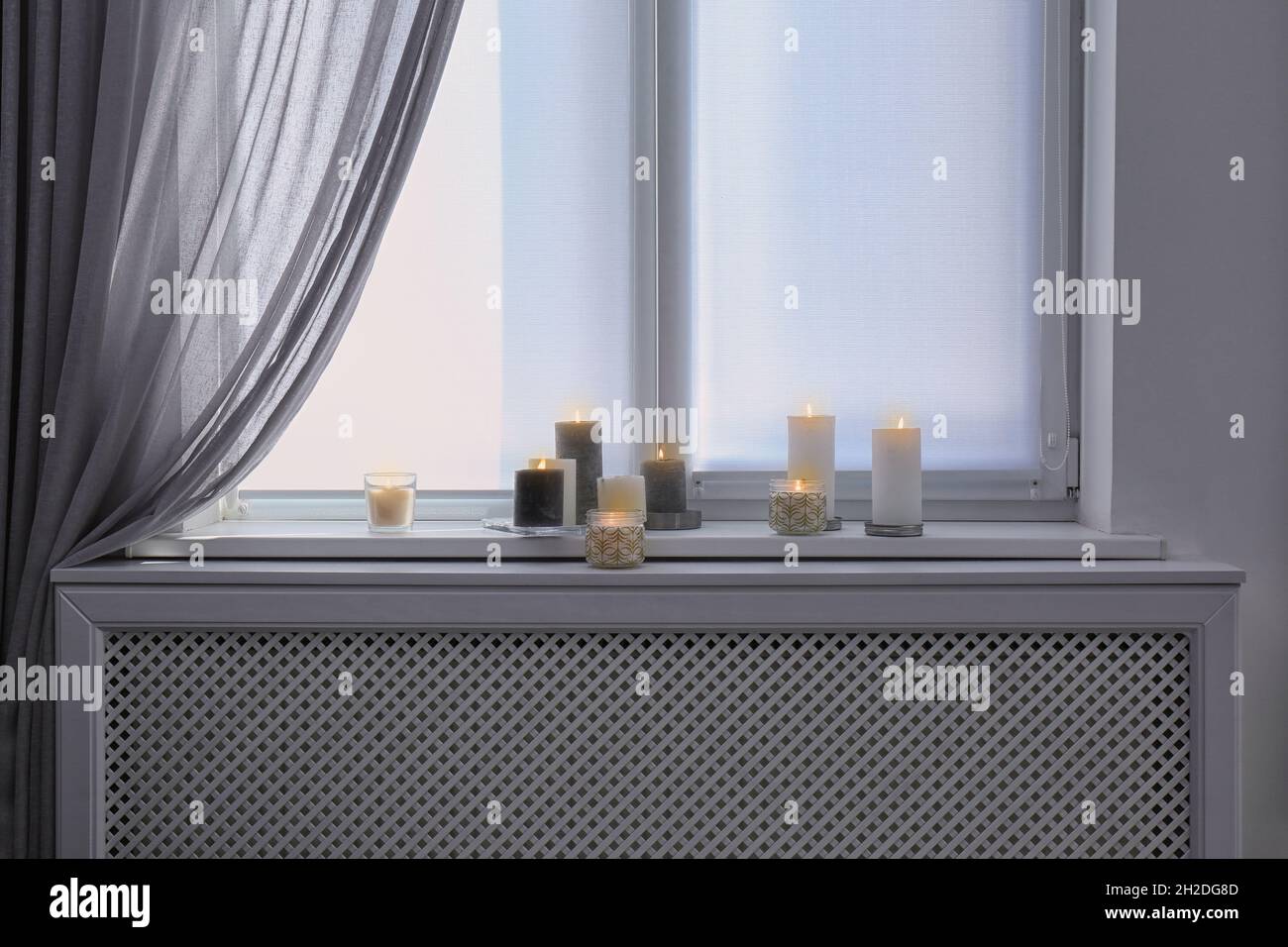 Burning candles on window sill in room Stock Photo Alamy