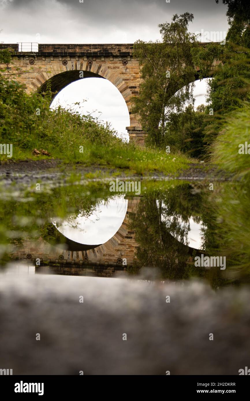 Reflection of railway bridge arches in a puddle Stock Photo